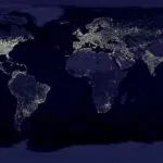 Satellite view of Earth at night with illuminated cities across continents.